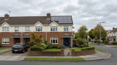 Solar panels installed on an Irish semi-detached house with green garden and overcast sky